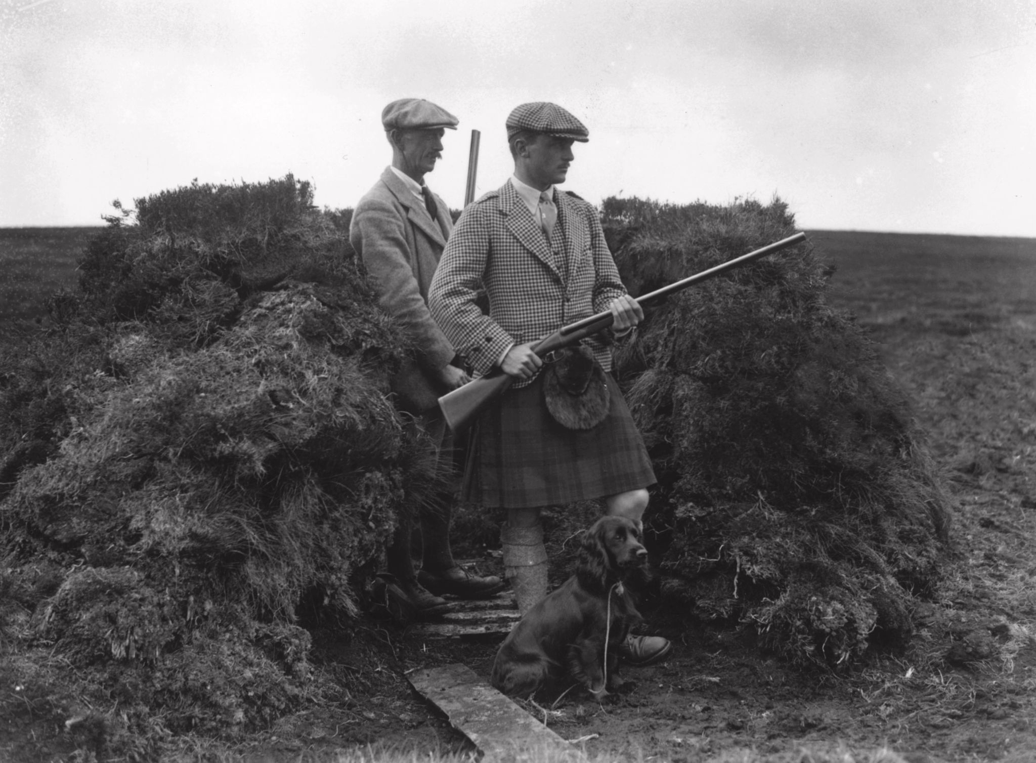 August 1922: M McDonald, a member of Lord Woolavington’s House Party, with a gamekeeper in a hide during a grouse shoot on Mannock Moors. (Photo by W. G. Phillips/Topical Press Agency/Getty Images)
